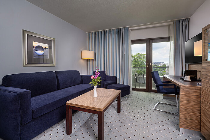 Heller Wohnbereich im Studio im Maritim Hotel Darmstadt mit bequemem Sofa und Zugang zum Balkon