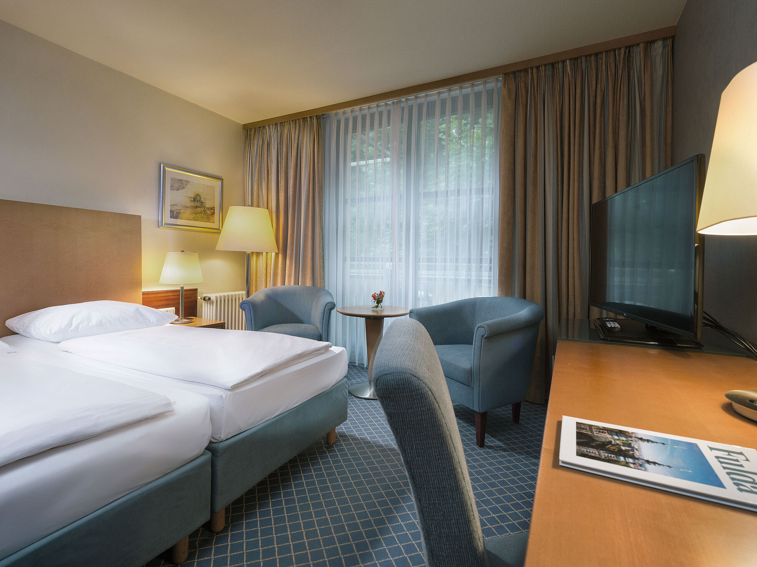 Comfort Doppelzimmer im Maritim Hotel Fulda mit modernen Möbeln, Schreibtisch und gemütlicher Sitzecke.