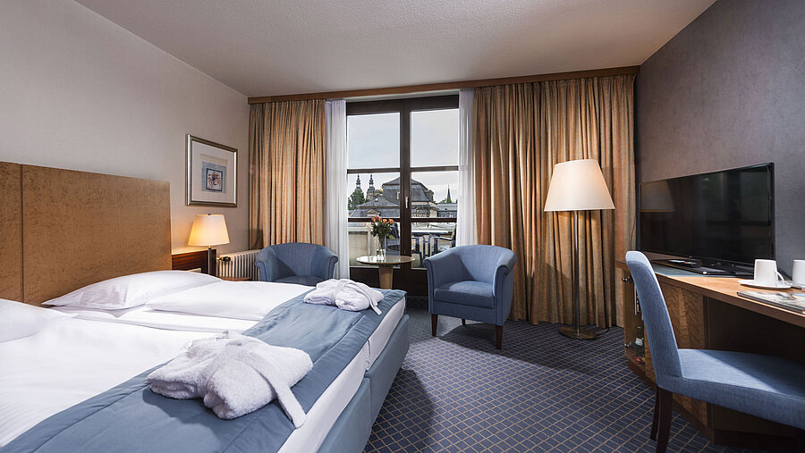 Elegantes Superior Zimmer im Maritim Hotel Fulda mit Doppelbett, Sitzbereich und Balkon mit Blick auf die Stadt.