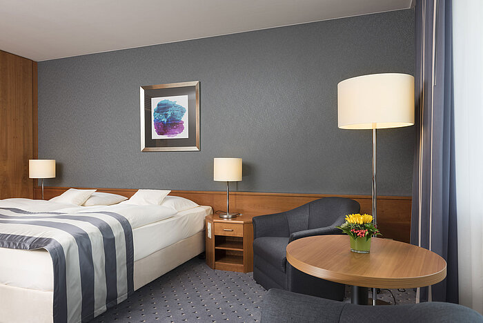 Komfortables Hotelzimmer im Maritim Hotel Ulm mit Doppelbett, Sitzbereich und stilvoller Einrichtung