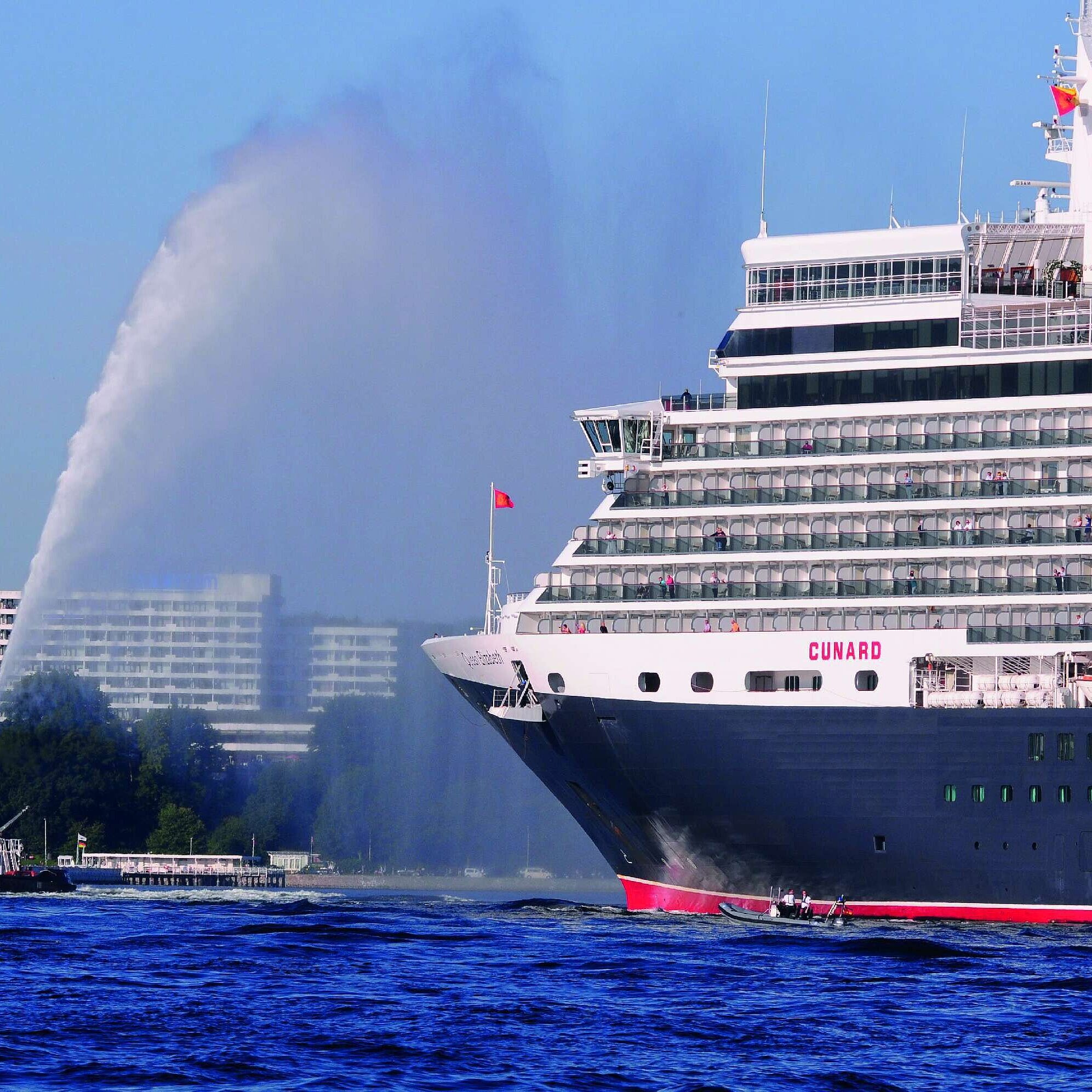 Außenansicht des Maritim Hotels Kiel, im Vordergrund das Kreuzfahrtschiff Queen Elizabeth und ein Schlepper auf dem Wasser.