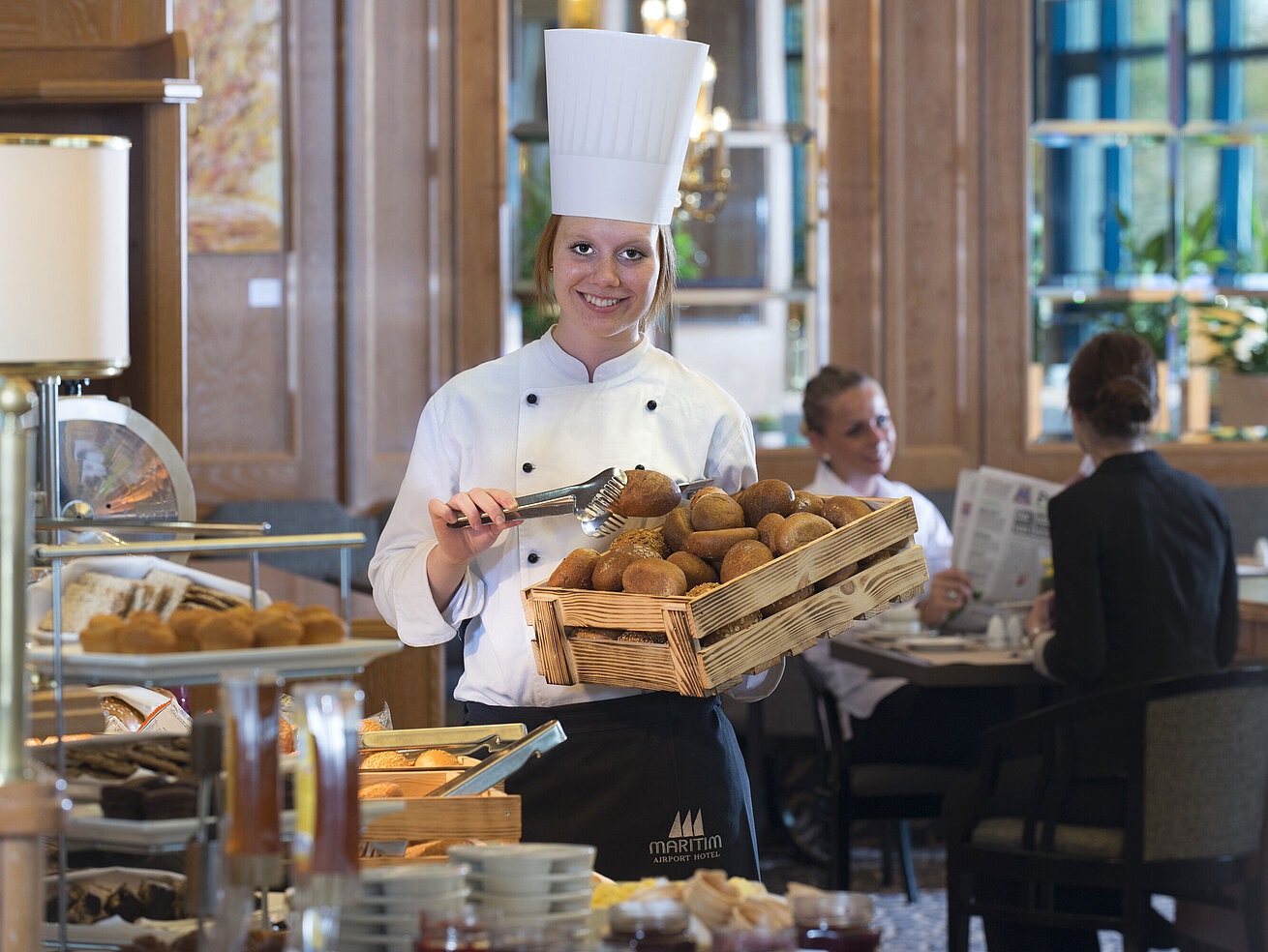 Freundliche Bäckerin präsentiert frische Brötchen am Frühstücksbuffet des Maritim Hotel Hannover.