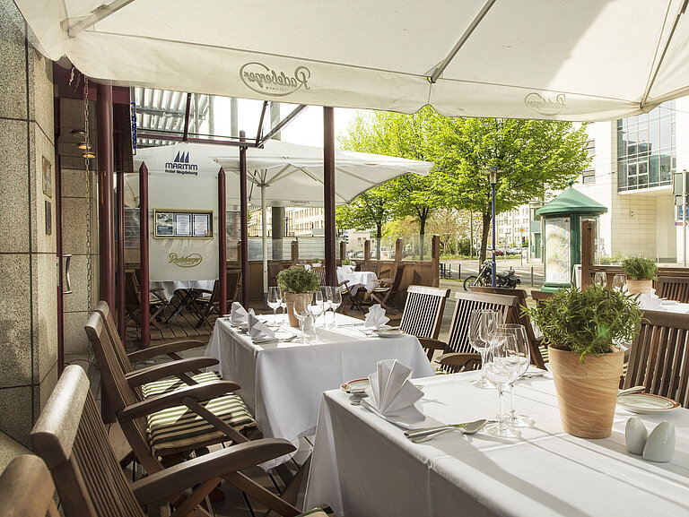 Die Terrasse des Maritim Hotels mit gedeckten Tischen, einer entspannenden Atmosphäre und viel natürlichem Licht im Außenbereich.