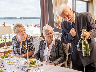 Ein Kellner präsentiert Gästen im Restaurant des Maritim Hotel Travemünde eine exklusive Weinauswahl.