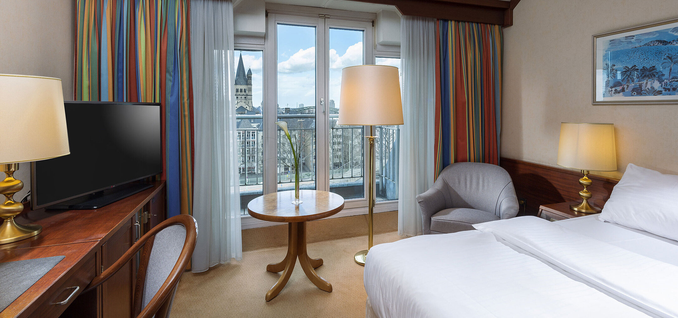 Classic Zimmer im Maritim Hotel Köln mit Doppelbett, Schreibtisch und Blick auf den Rhein sowie das historische Stadtzentrum.