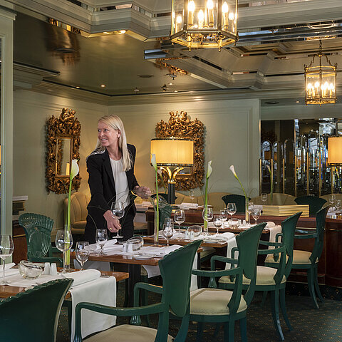 Restaurant "La Galerie" im Maritim Hotel Köln mit gedeckten Tischen und einer Mitarbeiterin, die das Restaurant vorbereitet.