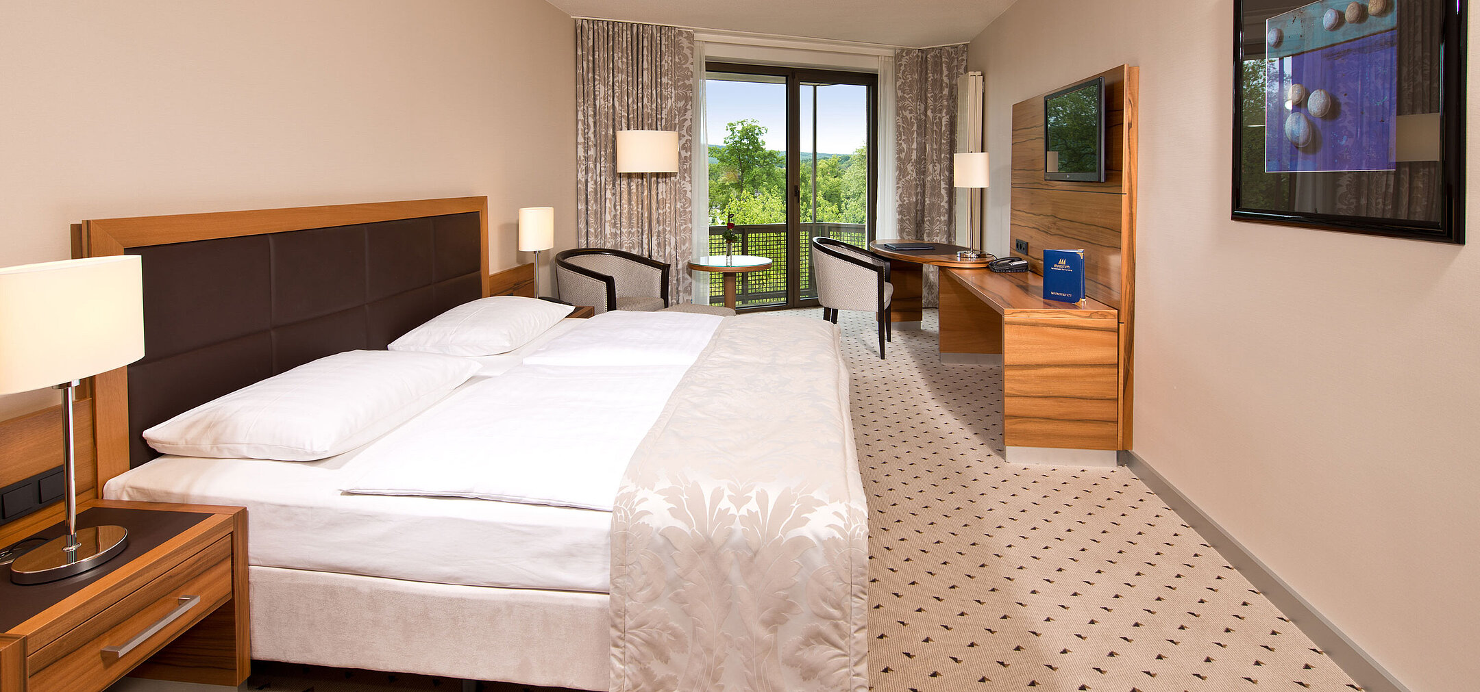 Helles Zimmer im Maritim Hotel Bad Homburg mit gemütlichem Bett, Schreibtisch und Balkon mit grünem Ausblick.