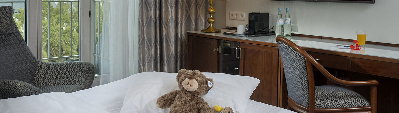 Familienzimmer im Maritim Hotel Köln mit TV, gemütlichen Kuscheltieren auf dem Bett und Blick auf den Rhein.