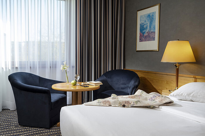 Sitzecke im Hotelzimmer mit Tisch, Buch, Glas Wasser und Apfel, perfekt zum Entspannen