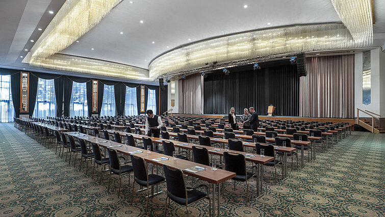 Prächtiger Saal im Maritim Hotel Magdeburg mit Bühne, Reihenbestuhlung und luxuriösem Kronleuchter.