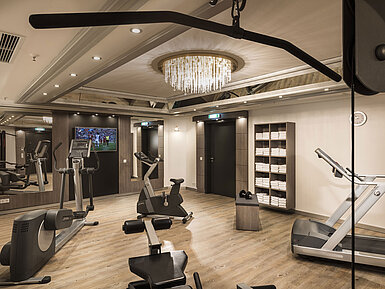 Gut ausgestatteter Fitnessraum mit Kardiogeräten und Spiegeln im Maritim Hotel München