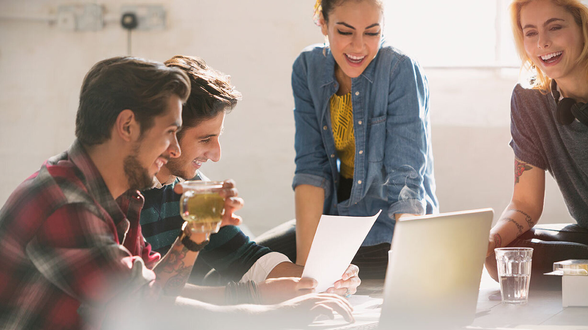 Junge Kollegen arbeiten gemeinsam an Laptop und Dokumenten im modernen Büro