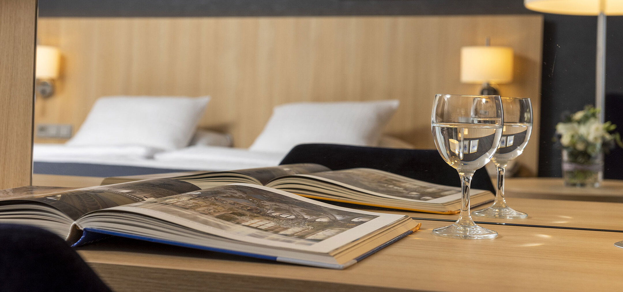 Gemütliches Comfort Zimmer im Maritim Hotel Würzburg mit Spiegel, offenem Bildband und Wassergläsern