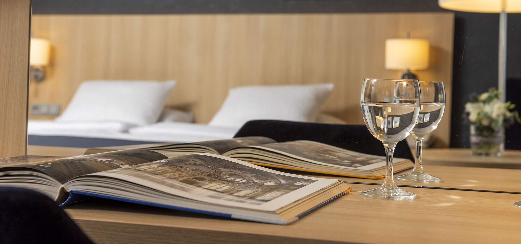 Gemütliches Comfort Zimmer im Maritim Hotel Würzburg mit Spiegel, offenem Bildband und Wassergläsern