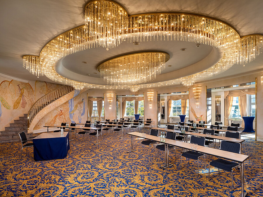 Fürst-von-Pückler-Saal mit großer Fensterfront, Reihenbestuhlung, markanten Deckenleuchten und hellem Ambiente.