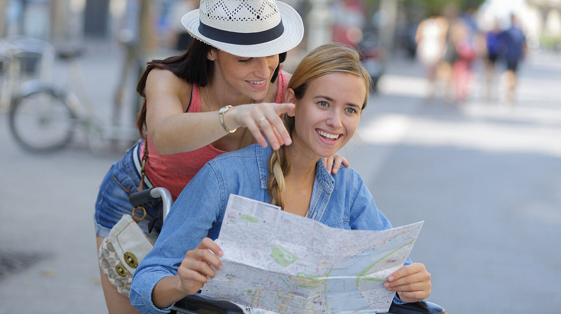 Zwei Frauen schauen gemeinsam auf einen Stadtplan während eines Stadtbummels.