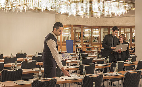 Mitarbeiter bereitet Konferenzraum mit Kristallleuchtern im Maritim Hotel München vor