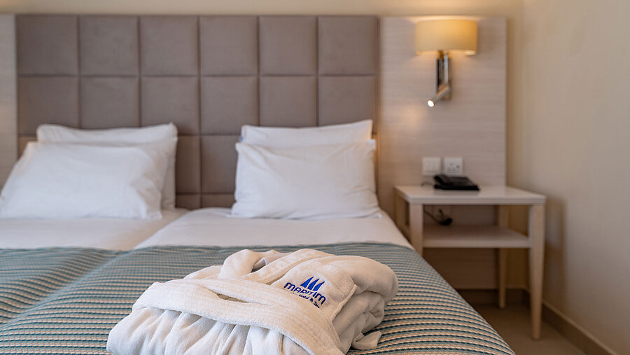 Detailansicht eines Hotelbetts mit Bademantel und weicher Bettwäsche