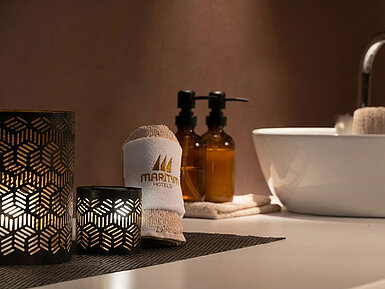 Stilvolles Badezimmer mit Maritim Handtuch, Pflegeprodukten und Waschbecken.