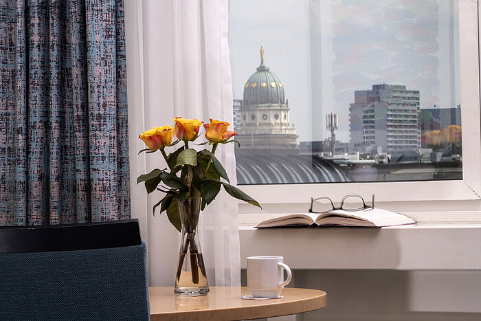 Vase mit gelben Rosen, Buch und Tasse am Fenster mit Blick auf den Französischen Dom im Maritim proArte Hotel Berlin