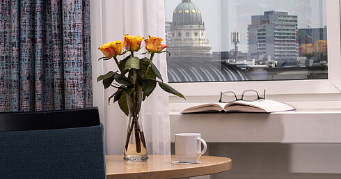 Vase mit gelben Rosen, Buch und Tasse am Fenster mit Blick auf den Französischen Dom im Maritim proArte Hotel Berlin