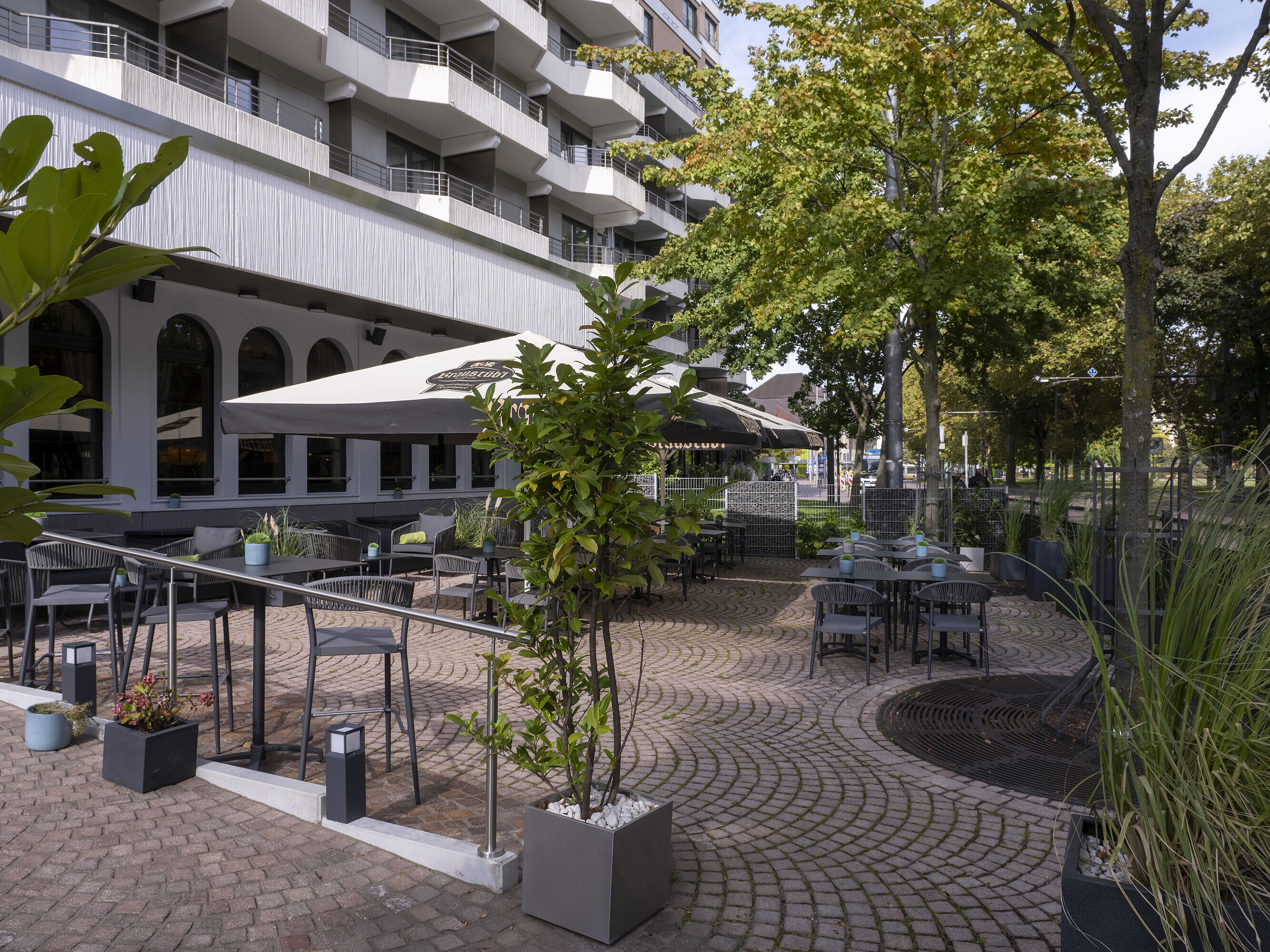 Sonnige Terrasse mit modernen Sitzmöglichkeiten und grüner Bepflanzung vor dem Maritim Hotel Darmstadt.