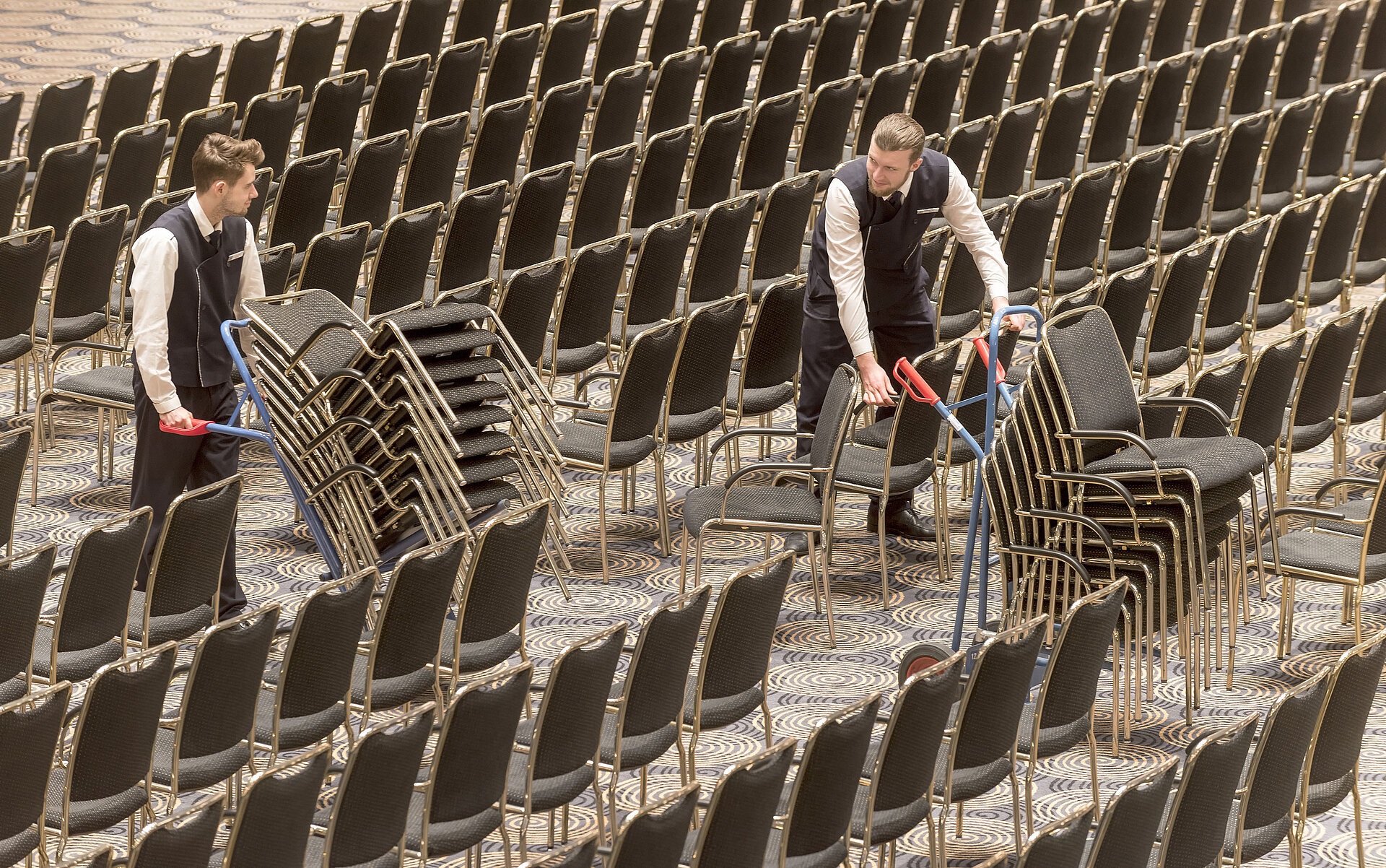 Saalbestuhlung | Maritim Hotel Bonn Mitarbeiter richten den Saal Maritim im Maritim Hotel Bonn ein und stapeln Stühle für eine Veranstaltung.