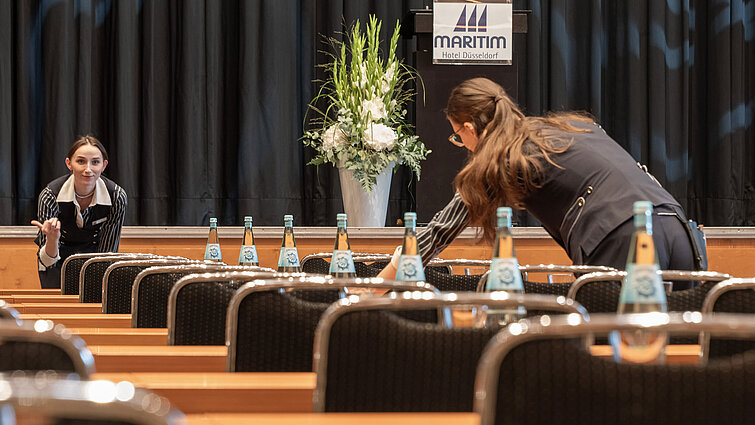 Mitarbeiter bereiten Tagungsraum mit Bühne im Maritim Hotel Düsseldorf vor.