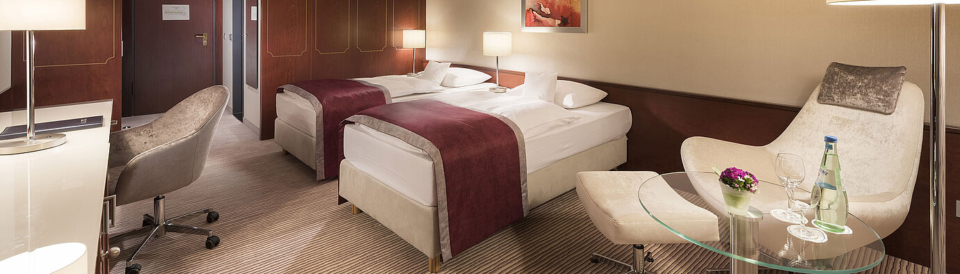Comfort Zimmer  Comfort Zimmer im Maritim Hotel Bonn, ausgestattet mit zwei Einzelbetten, Sessel, Schreibtisch und moderner Beleuchtung.