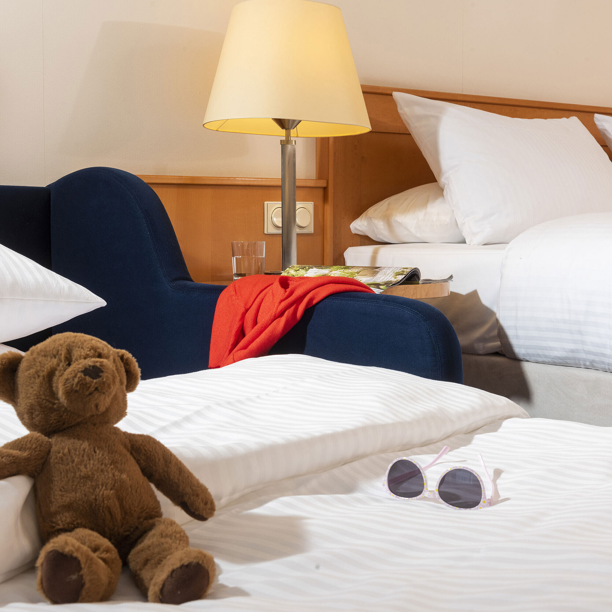 Gemütliches Familienzimmer im Maritim Hotel Frankfurt mit Kuscheltier, Sonnenbrille und weichen Betten.