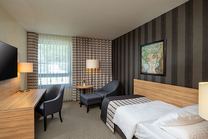 Classic Einzelzimmer im Maritim Hotel Königswinter mit Einzelbett, Sitzecke und großem Fenster.