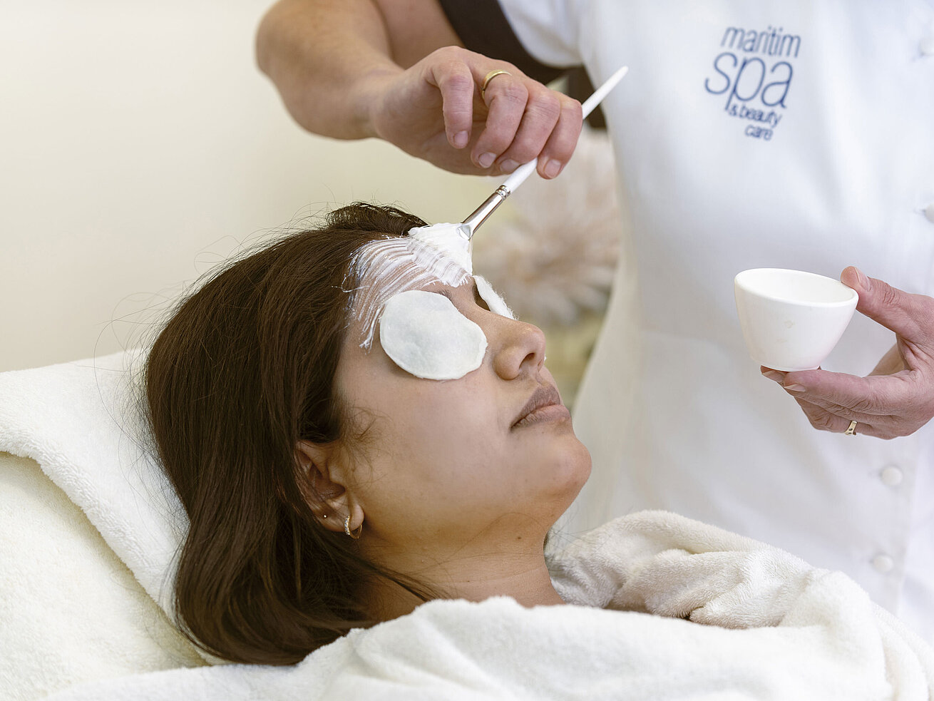 Gesichtsbehandlung Gesichtsbehandlung im Maritim Hotel Spa: Eine Frau erhält eine Gesichtsmaske und entspannende Pflege mit Baumwollpads.