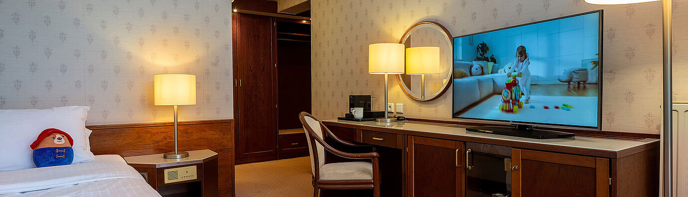 Superior Familienzimmer mit Bett, großem TV, Schreibtisch und gemütlicher Sitzecke für einen entspannten Aufenthalt.