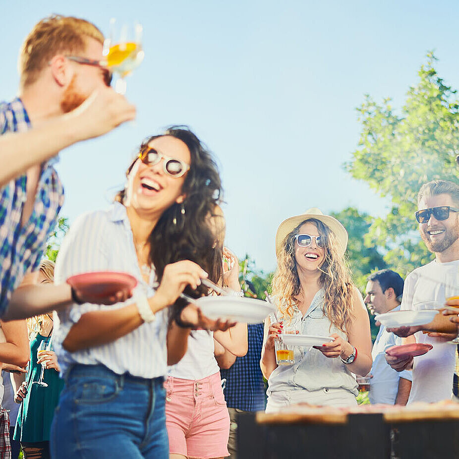 Freunde lachen und feiern gemeinsam bei einer sommerlichen Grillparty im Freien