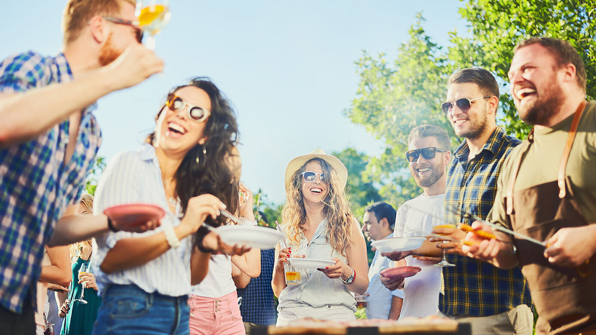 © chika milan - AdobeStock.com Freunde lachen und feiern gemeinsam bei einer sommerlichen Grillparty im Freien