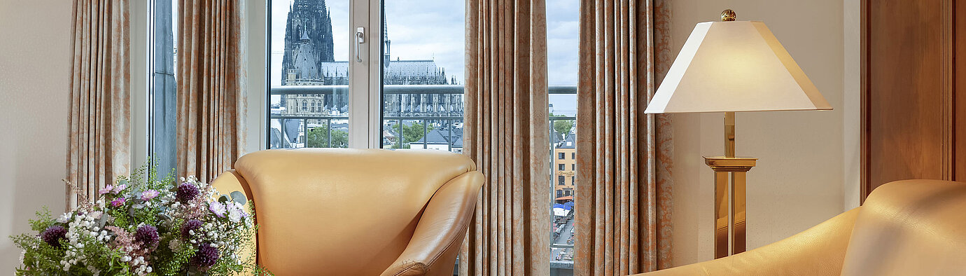 Elegante Heumarkt-Suite im Maritim Hotel Köln mit komfortablen Ledersesseln und direktem Blick auf den Kölner Dom.