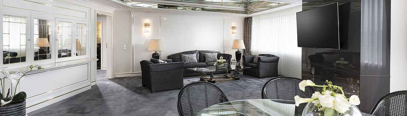 Luxus Suite  Stilvolles Wohnzimmer der Luxus-Suite im Maritim Hotel Bonn mit Spiegeldecke, modernen Möbeln und einem großen Esstisch.