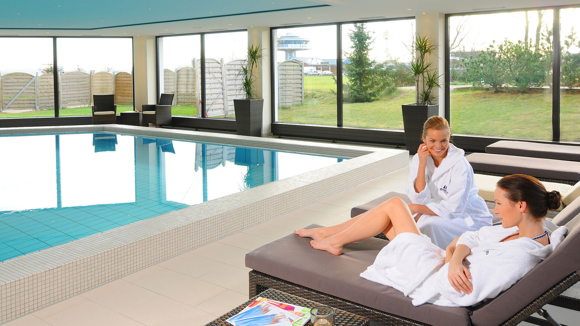 Zwei Frauen entspannen im Bademantel auf Liegen am Innenpool des Maritim Hotel Travemünde