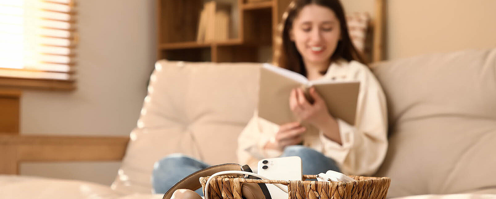 Junge Frau entspannt auf dem Sofa mit Buch – gemütlicher Moment zu Hause mit Fokus auf Ruhe und Entspannung