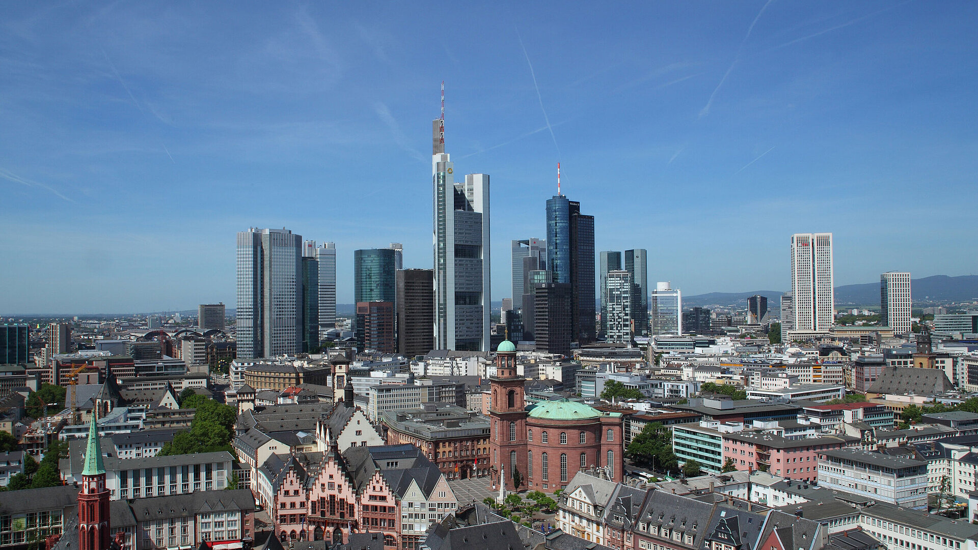 Blick auf die Skyline von Frankfurt mit dem Römer und der Paulskirche im Vordergrund bei klarem Himmel.