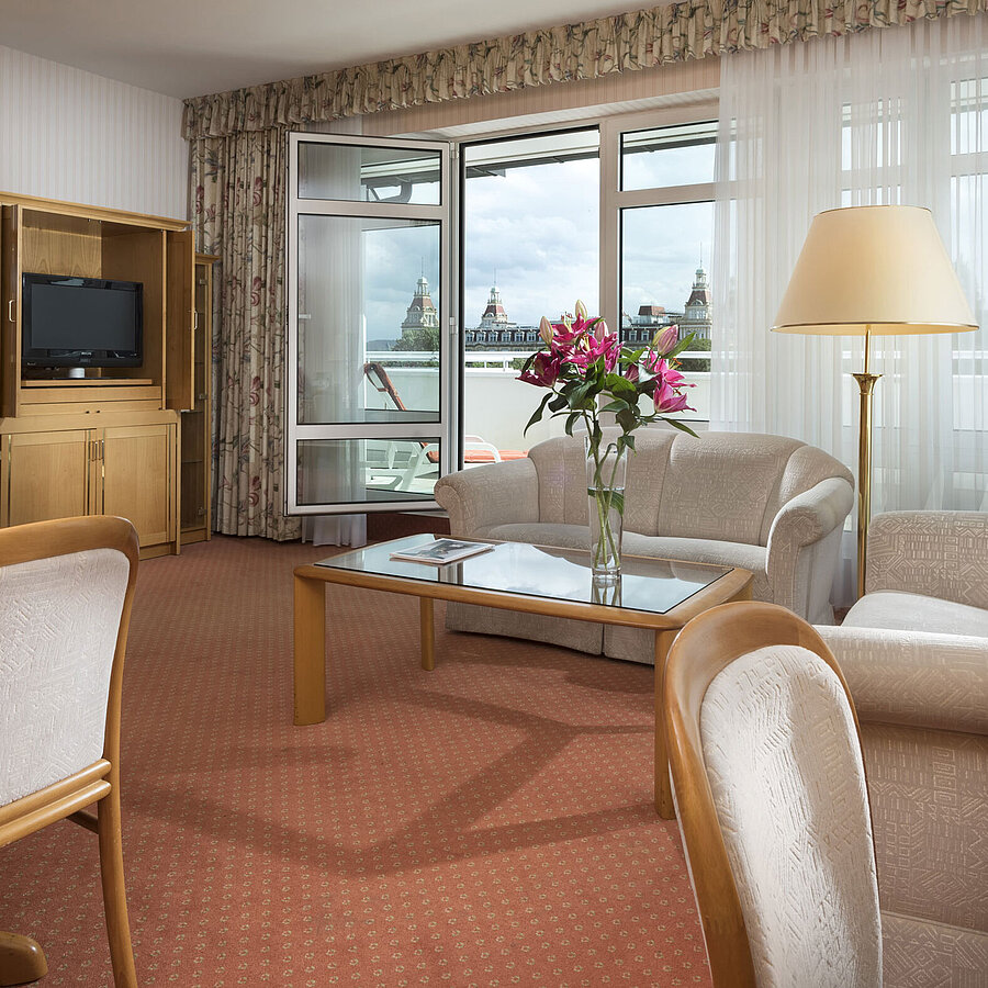 Großzügiger Wohnbereich mit Blumen, Sofa, Esstisch und Ausblick im Maritim Hotel Bad Wildungen