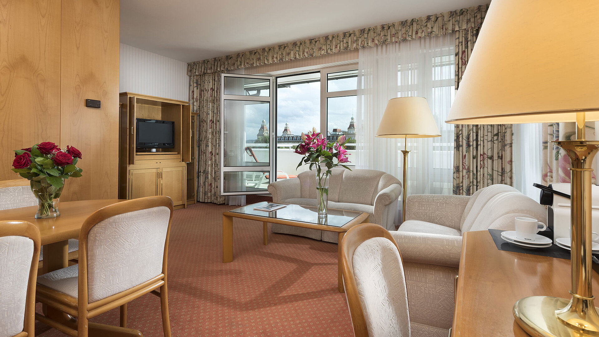Großzügiger Wohnbereich mit Blumen, Sofa, Esstisch und Ausblick im Maritim Hotel Bad Wildungen