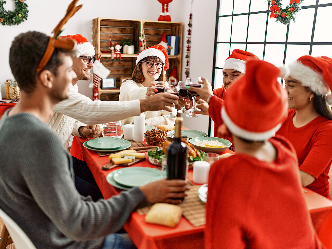 Freunde stoßen beim festlichen Weihnachtsessen mit Rotwein an