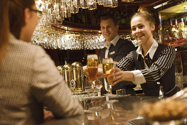 Zwei Mitarbeitende servieren frisch gezapfte Getränke an der Bar im Maritim Hotel Ulm