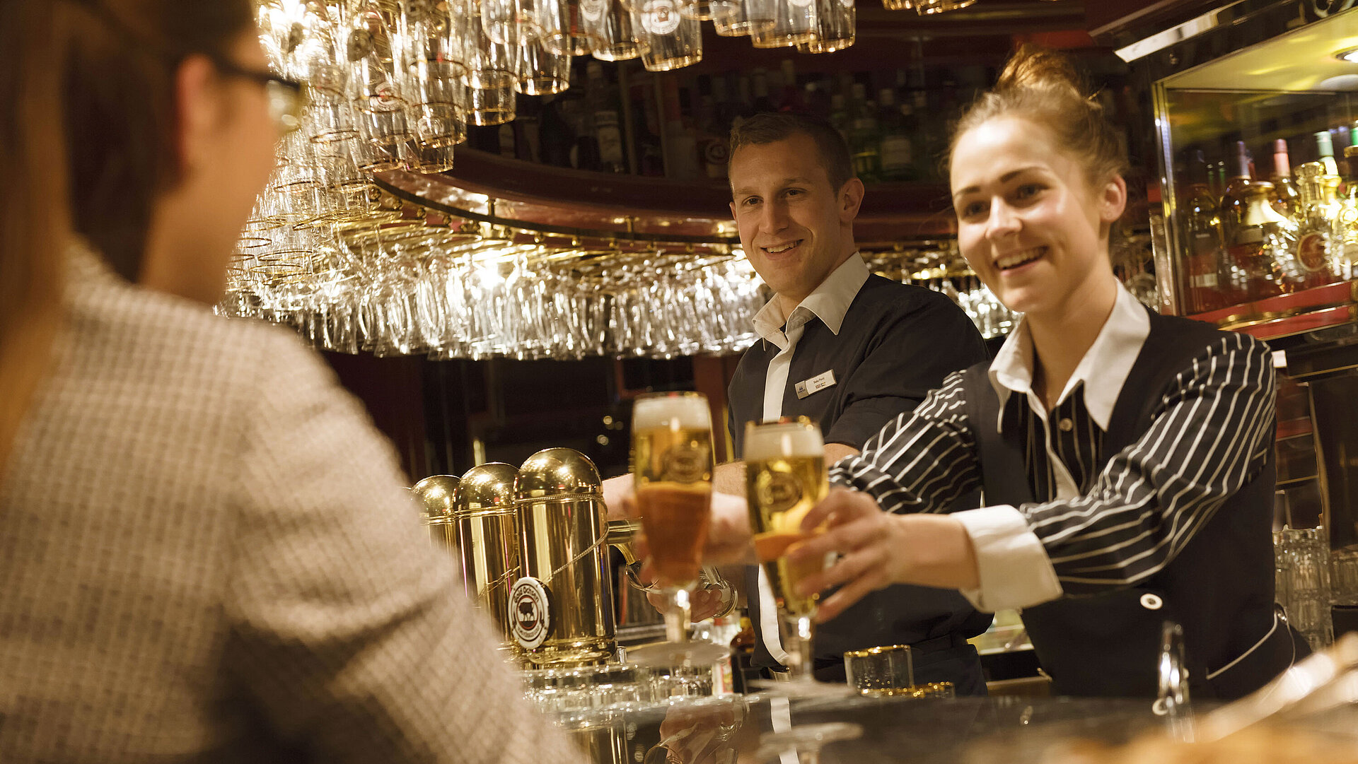 Zwei Mitarbeitende servieren frisch gezapfte Getränke an der Bar im Maritim Hotel Ulm