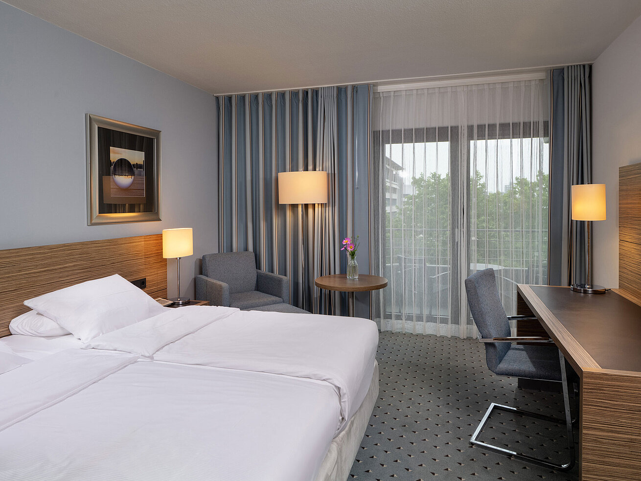 Gesamtansicht des Comfort Zimmers im Maritim Hotel Darmstadt mit Bett, Schreibtisch und Zugang zum Balkon