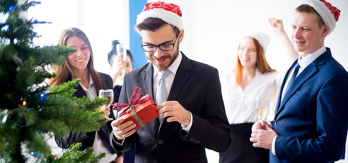 © Nichizhenova Elena - AdobeStock.com Kollegen beschenken sich bei einer Weihnachtsfeier im Hotel