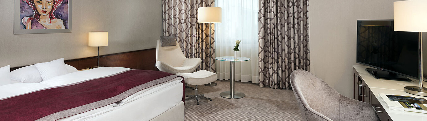 Comfort Zimmer  Comfort Zimmer im Maritim Hotel Bonn mit gemütlichem Bett, Sesseln, Schreibtisch und modernen Vorhängen.