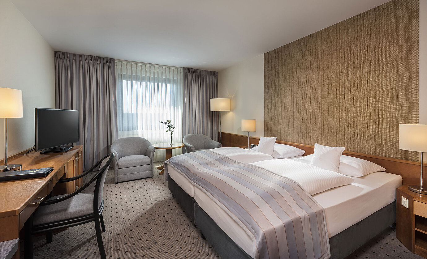 Modernes Classic Doppelzimmer mit gemütlichem Doppelbett, Sitzbereich und Schreibtisch im Maritim Hotel Hannover.