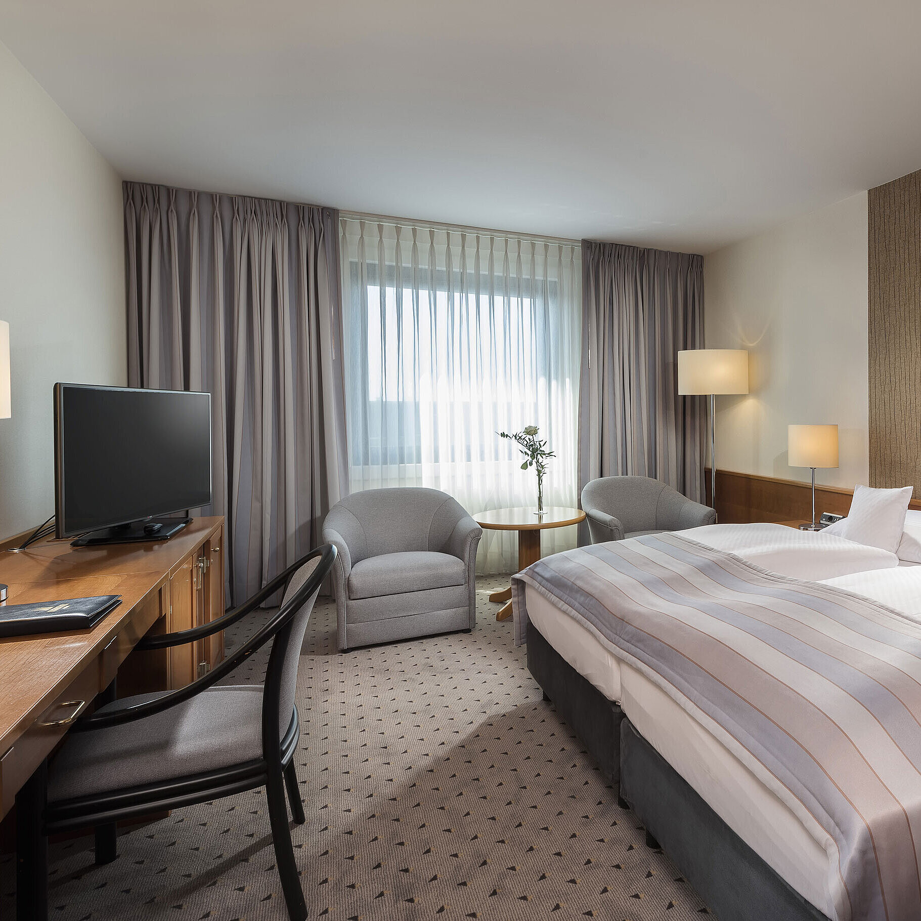 Modernes Classic Doppelzimmer mit gemütlichem Doppelbett, Sitzbereich und Schreibtisch im Maritim Hotel Hannover.